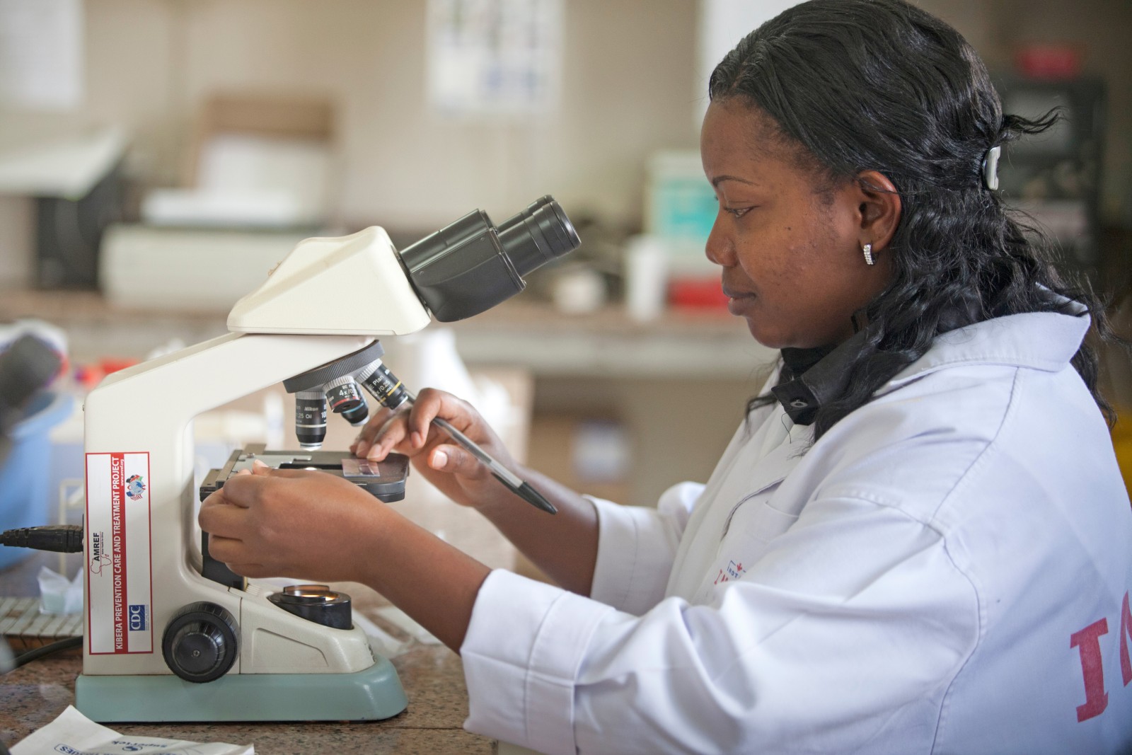 A researcher in Kenya inserts a slide under a microscope